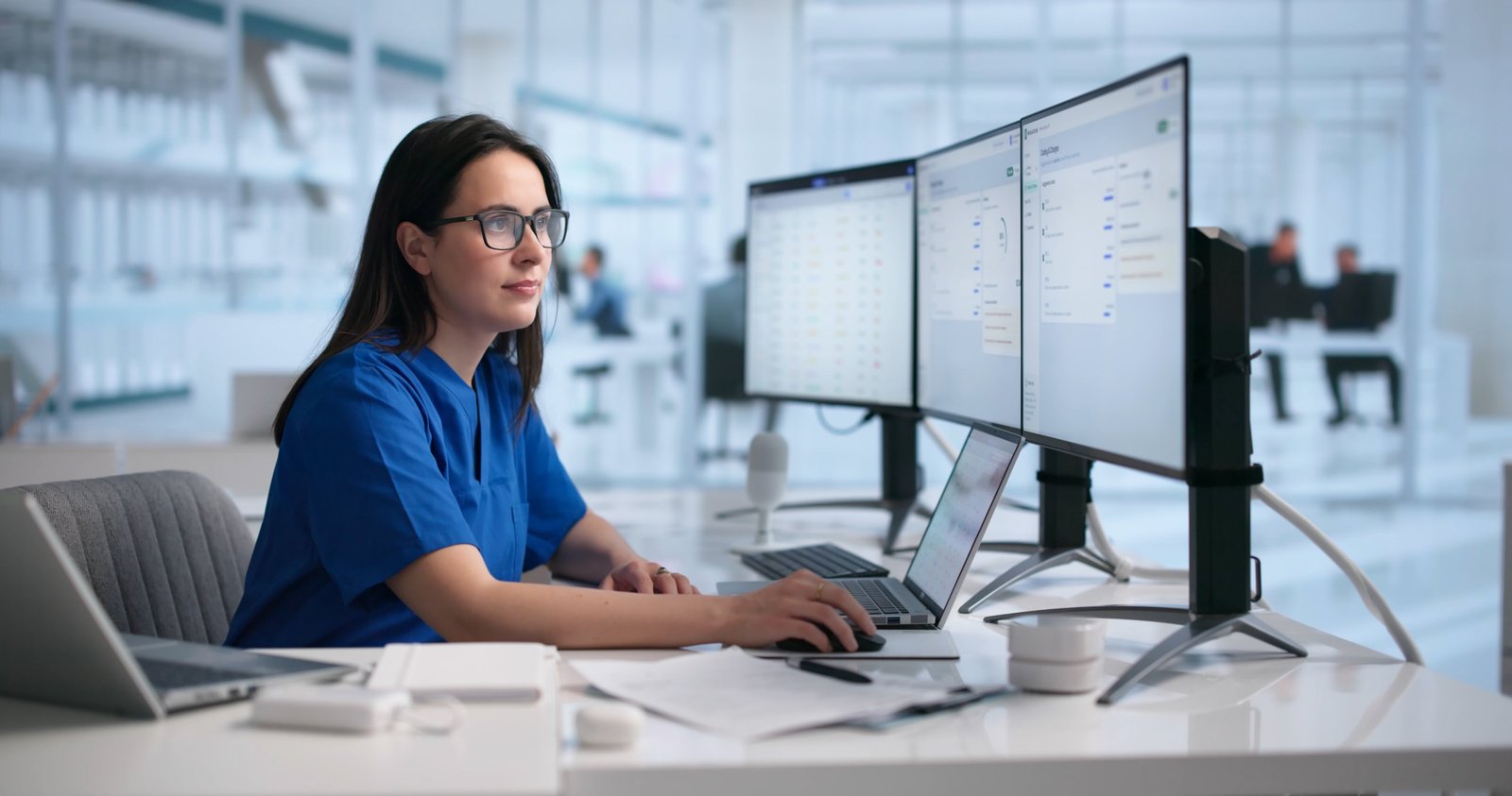 Clinician reviewing a credentialing dashboard across multiple monitors